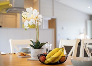 A dining table with a fruit bowl, a potted plant, and a glass of water.
