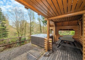 A wooden cabin with a hot tub and picnic table on a deck. - Timber lodge set in an elevated position with views of the lake. (Webbery, Bideford)