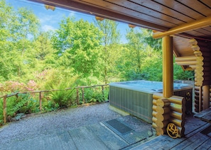 Un bain à remous dans un chalet en bois, entouré d’une végétation luxuriante.