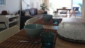 A dining area with a table set for four, a sofa, a floor lamp, and a view of the outdoors. - Costa Adeje Holiday Apartment (Adeje)