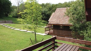 A wooden cabin with a sloped roof, surrounded by a grassy area and a wooden deck. - Single storey A-frame lodge. (North Tamerton, Bude)