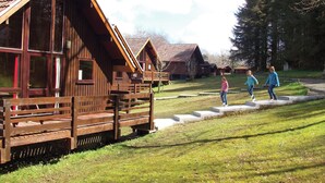 Wooden cabins with large windows, a grassy area, and a clear sky. - Single storey A-frame lodge. (North Tamerton, Bude)