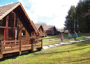 Holzbungalows mit großen Fenstern, einer Rasenfläche und blauem Himmel.