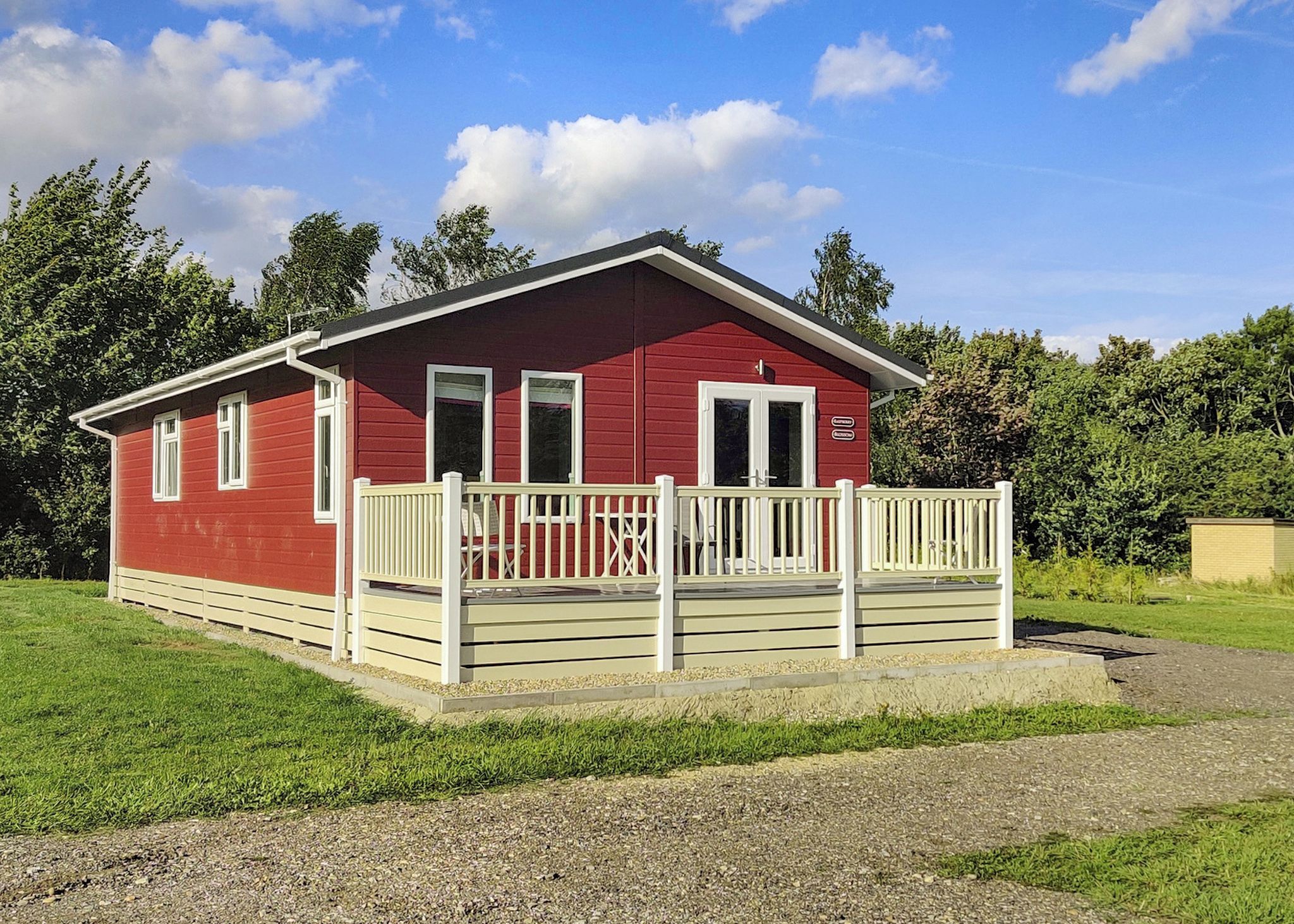 A red building with a white porch and a gravel driveway.