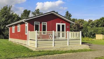 A red building with a white porch and a gravel driveway.
