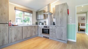 Cuina moderna amb armaris de fusta, forn de pared i finestra amb vista a vegetació.