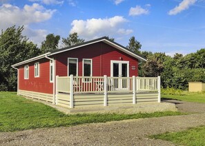 A red building with a white porch and a gravel driveway.