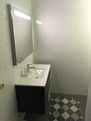 Bathroom features a white vanity, large mirror, and black cabinet.