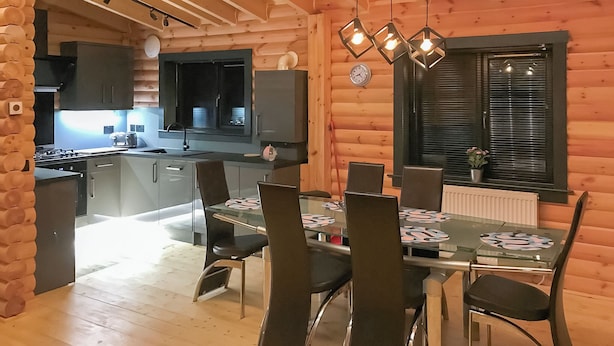 Ein Interieur einer Holzhütte mit Küche, Essbereich und einem Fenster mit Jalousien.
