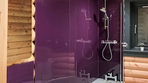 Ein modernes Badezimmer mit einer gläsernen Duschkabine, einer weißen Badewanne und Holzvertäfelung an den Wänden.