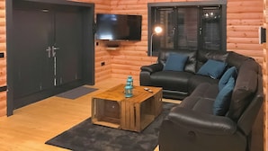 Ein Holzblockhaus-Innenraum mit einer Couch, einem Fernseher und einem Holztisch.