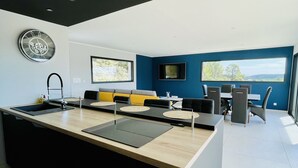 Et moderne køkken med en central ø, en integreret vask og et fladskærms TV ophængt på væggen.