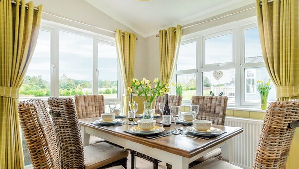 Comedor con una mesa para cuatro, sillas de mimbre y vistas al exterior.