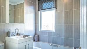 Un bagno moderno con lavabo, specchio, vasca e finestra.