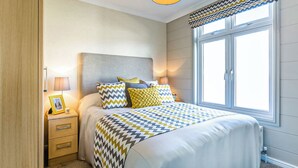 Una camera da letto con un letto, comodini, una lampada, un portafoto e una finestra con tende.