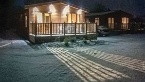 Un sentiero innevato che conduce a una casa di legno con veranda.