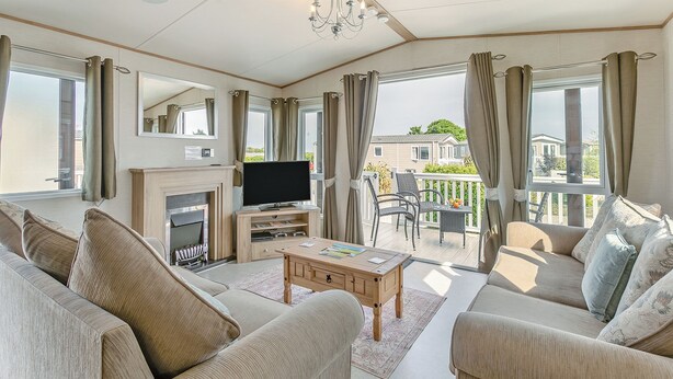 Un salon spacieux doté d’une cheminée, d’un téléviseur à écran plat et d’un balcon aménagé avec du mobilier d’extérieur.