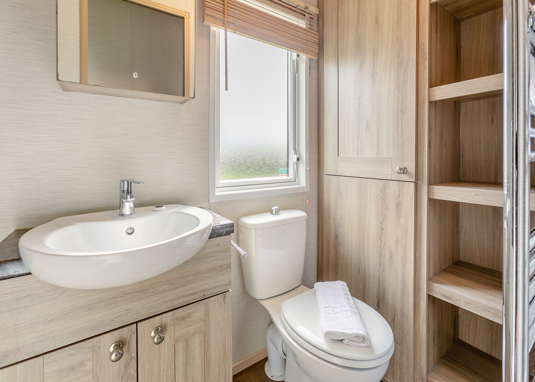 A bathroom with a sink, toilet, and a mirror.