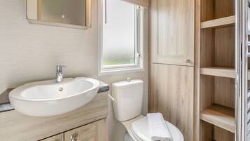 A bathroom with a sink, toilet, and a mirror.