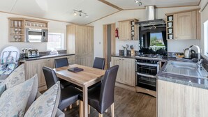 Une cuisine compacte avec un coin repas, des placards en bois, un four à micro-ondes, une cuisinière et un évier.