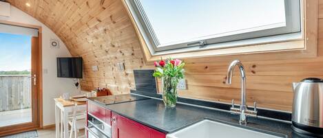 Una cocina moderna con un amplio ventanal, techo de madera y armarios rojos.