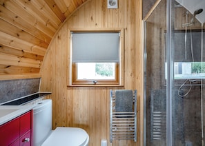 A wooden cabin bathroom with a toilet, a sink, a window, and a shower. - 0 bedroom accommodation in Great Busby (Great Busby)