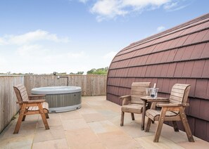 Boblebad, træstole og et bord med glas og en flaske på en terrasse med stenfliser.