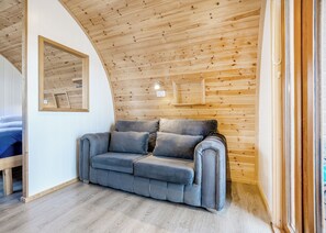 A cozy room with a curved ceiling, a grey sofa, and a wooden wall.