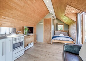A compact, modern room with a kitchenette, a bed, and a window.
