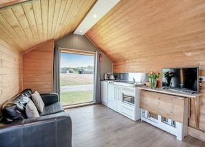 A cozy, modern kitchen with a large window, a flat-screen TV, and a built-in oven.