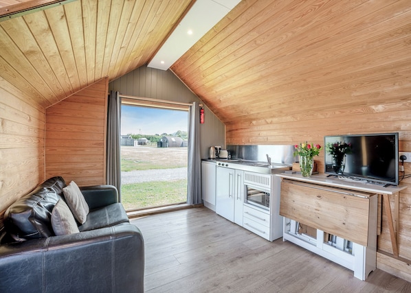 A cozy, modern kitchen with a large window, a flat-screen TV, and a built-in oven.