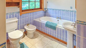 A bathroom with a toilet, bidet, bathtub, and sink.