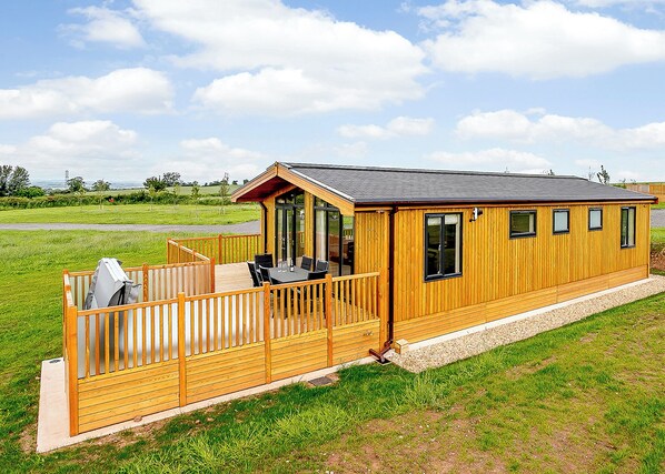 Une cabane en bois dotée d’une terrasse, d’un patio couvert et offrant une vue sur le paysage environnant.