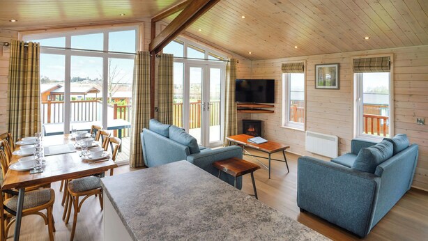 Un intérieur de chalet chaleureux comprenant un coin repas, des canapés, un téléviseur et une cheminée.
