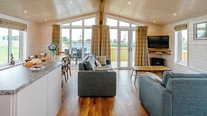 Un intérieur de cabine spacieux comprenant une cuisine, un coin repas et un espace salon, avec de grandes fenêtres et une cheminée.