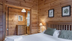 A wooden-paneled bedroom with a bed, bedside lamp, and framed artwork. - 2 bedroom accommodation in Ellesmere (Ellesmere)