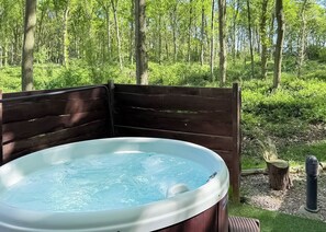 A hot tub in a wooded area with a wooden deck.