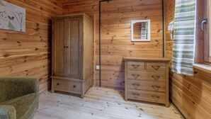 A wooden room with a wardrobe, a dresser, a mirror, and a green chair. - 2 bedroom accommodation in Ellesmere (Ellesmere)
