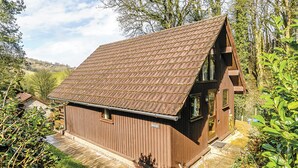 A wooden cabin with a sloped roof, surrounded by greenery. - 2 bedroom accommodation in Waterrow, Wiveliscombe (Waterrow, Wiveliscombe)