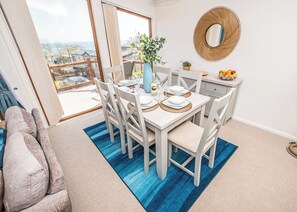 A dining area with a table set for four, a large window, and a view of the outside.
