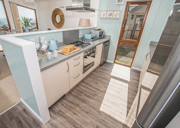 A modern kitchen with a gas stove, microwave, and a refrigerator.