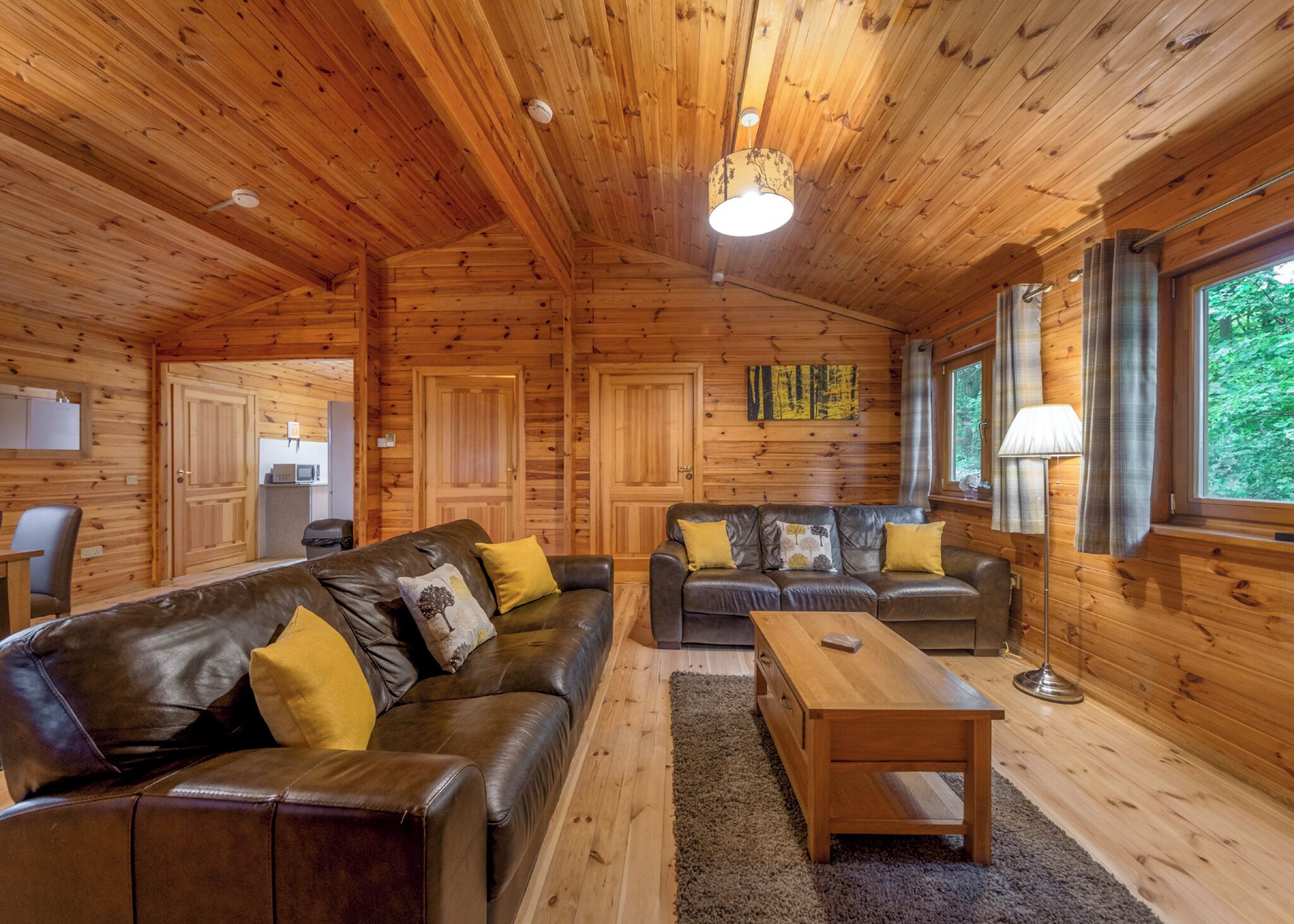 Ein Holzblockhaus-Interieur mit einer Couch, Sesseln, einem Couchtisch und einem Esstisch.