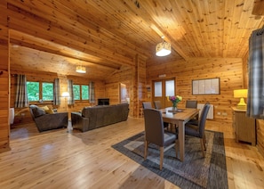 L’intérieur d’un chalet en bois, avec un canapé, une table à manger, des chaises et un téléviseur.
