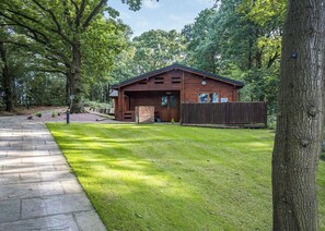 A wooden cabin with a stone pathway leading to it, surrounded by lush greenery. - Woodland Birch Lodge (Ellesmere)
