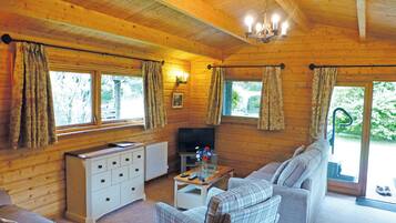 L'intérieur d'un chalet en bois, avec un canapé, un téléviseur et une petite table.
