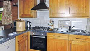 A kitchen with wooden cabinets, a gas stove, a sink, and a dishwasher. - Timber lodge with one queen size double and one twin. (Kentisbeare, Nr Cullompton)
