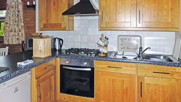 Une cuisine avec des meubles de rangement en bois, une cuisinière à gaz, un évier et un lave-vaisselle.