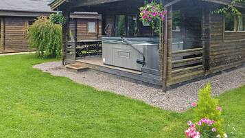 Une cabane en bois dotée d’un patio, d’un jacuzzi et d’une petite terrasse.
