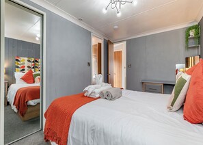 Un dormitorio moderno con cama, espejo, mesita de noche y armario.