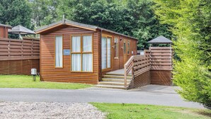 A wooden cabin with a porch, a door, and a window. - Buxton Lodge with hot tub (Longnor, Nr. Buxton)